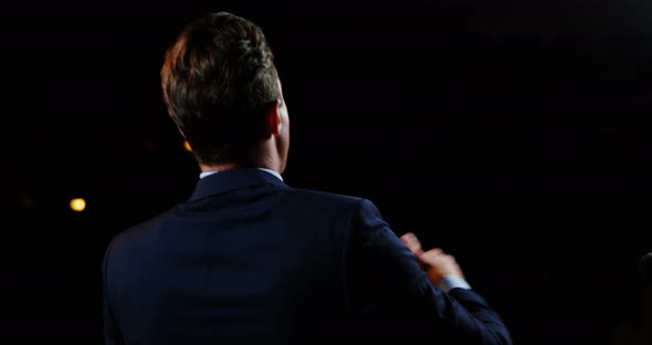 Rear view of male business executive giving a speech alt