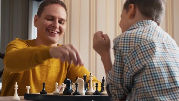 Caucasian father playing checkmate with his son