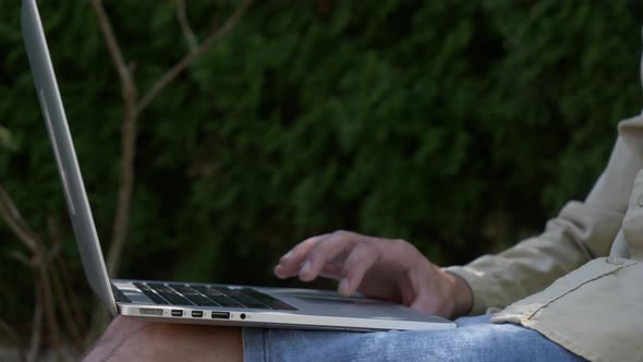 Stylish man working with laptop in a garden