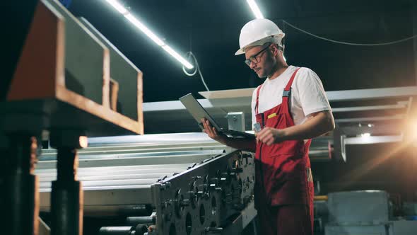 Specialist with a Laptop Is Watching the Spinning Conveyor alt