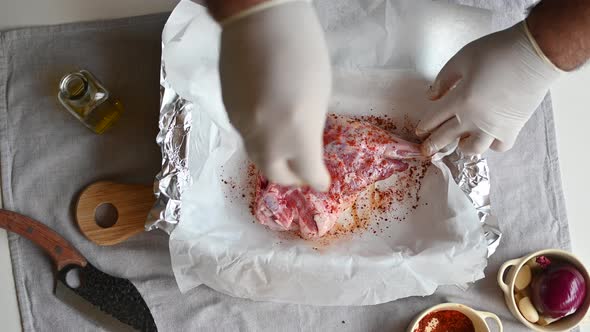 Chef Sprinkles Spices on a Leg of Lamb Before Roasting Top View