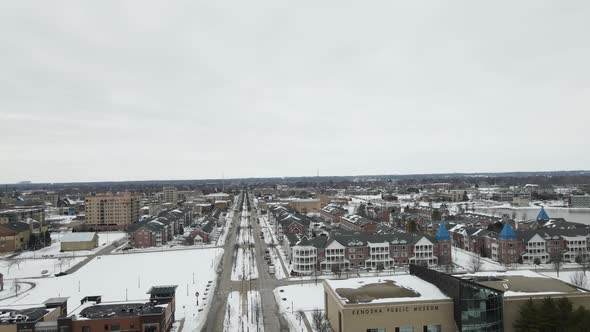 Aerial view of large housing complex and businesses in winter with snow covered park.