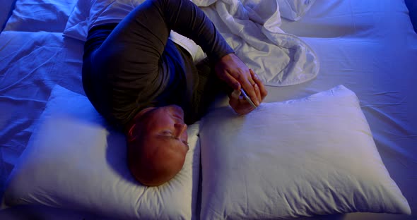 Close-up Portrait of a Bald, Middle-aged Man Lying in Bed with White Linens and Two Pillows. He Lies alt