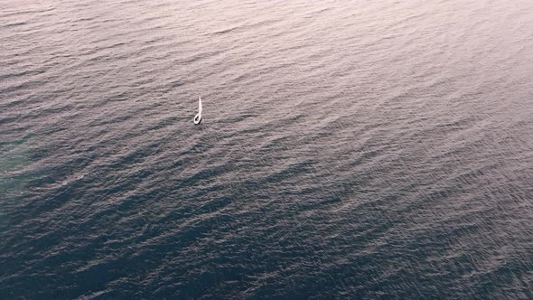 Lonely boat sailing on a lake at sunset. alt