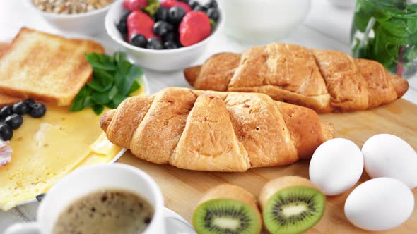 Closeup Two Big Fresh Appetizing Croissant on Wooden Board Surrounded By Tasty Breakfast Food alt