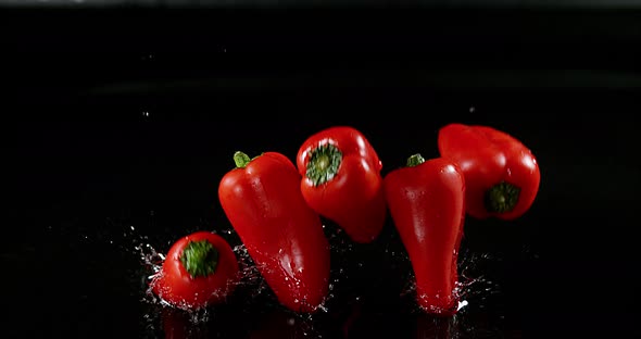 Red Sweet Peppers, capsicum annuum, Vegetable falling on Water against Black Background alt
