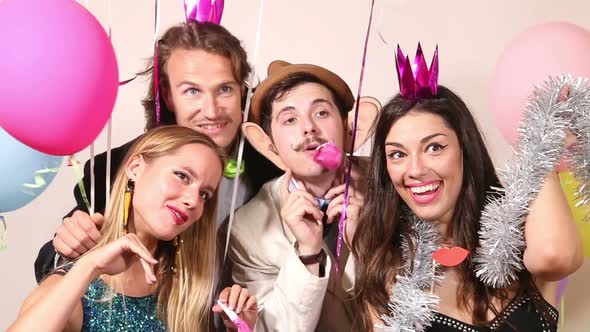 Group of young friends having a great time in party photo booth alt