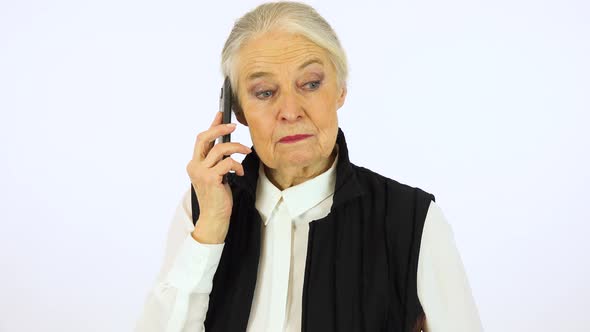 An elderly woman talks on a smartphone with a smile - white screen studio alt