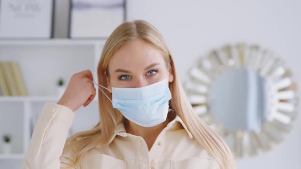 Young attractive girl taking off the medical blue mask. Beautiful smiling woman without medical mask alt