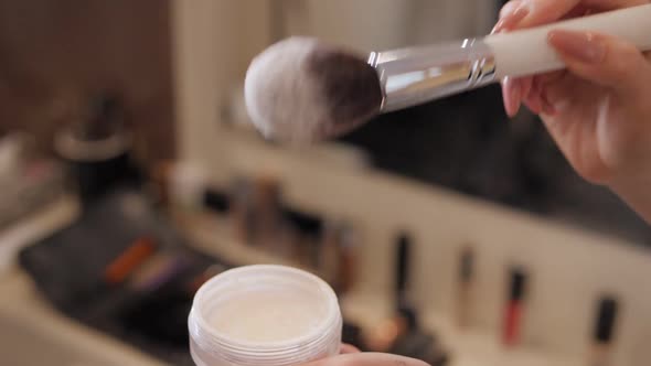 Closeup of a Makeup Artist Holding in Hands Brush and Powder alt