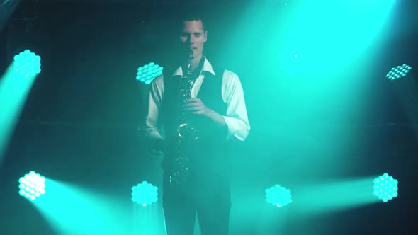 A Young Retro Stylish Guy Plays on the Golden Shiny Saxophone in the Turquoise Spotlights on Stage alt