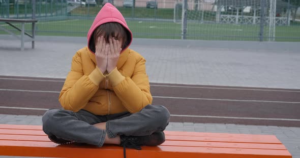 Upset Child Sitting on Playground alt