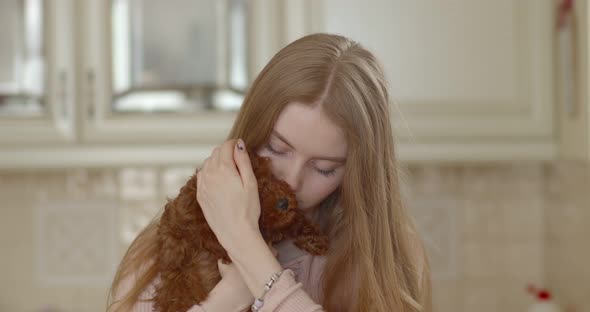 Young beautiful girl holding a poodle puppy in her arms. presses to itself. The puppy yawns.