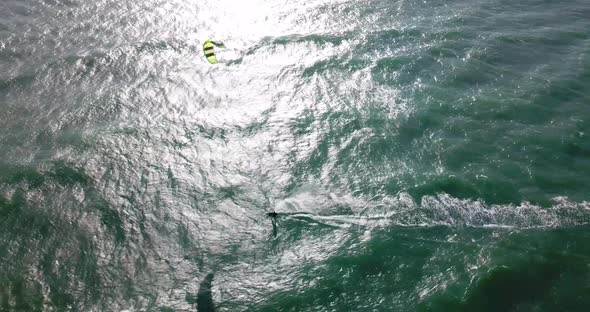 Aerial drone view of a man kiteboarding on a kite board. alt