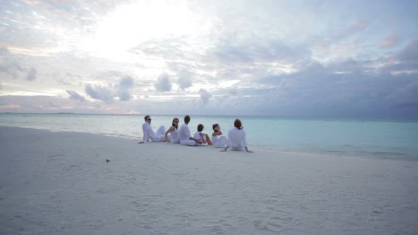 Family Sitting Together at Sunset on Tropical Beach
