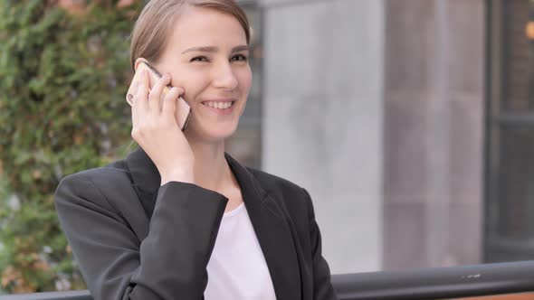 Young Businesswoman Talking on Phone Sitting Outdoor alt