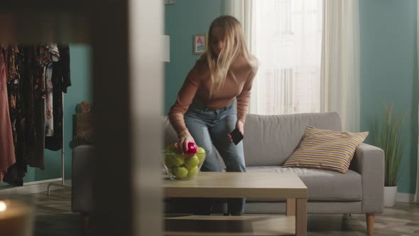 Girl Enters the Room with the Phone and Takes the Apple