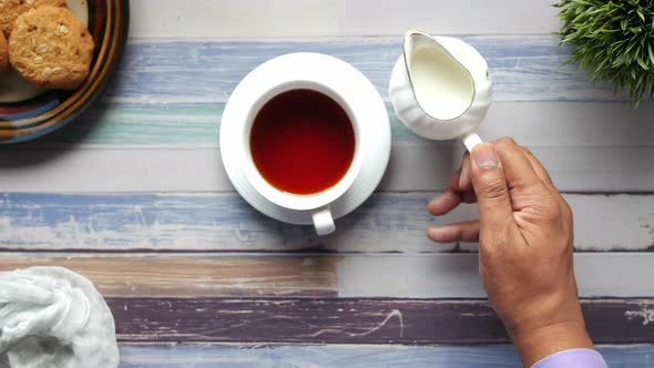 Top View of Man Hand Pouring Milk in a Tea Pot alt