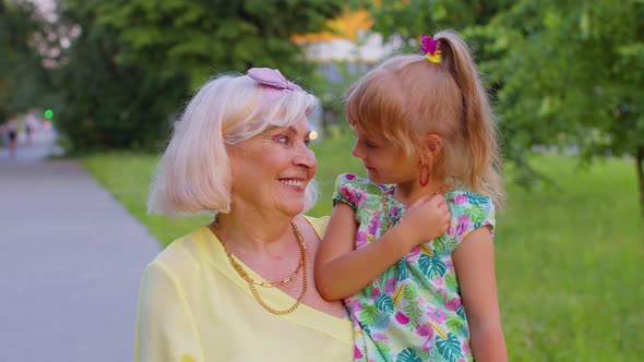 Little Granddaughter Child Embracing Kissing with Her Grandmother in Park Happy Family Relationship alt