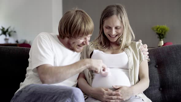 Front View of Happy Couple Sitting and Playing with Booties alt