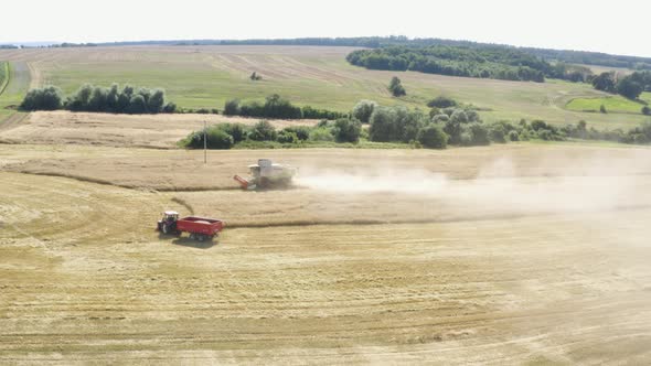 Aerial Drone Shot  a Combine Harvester and a Tractor in a Field in a Rural Area on a Sunny Day alt