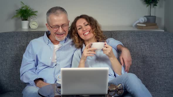 A Happy Middleaged Couple Watches a Funny Movie on Their Laptop and Laughs