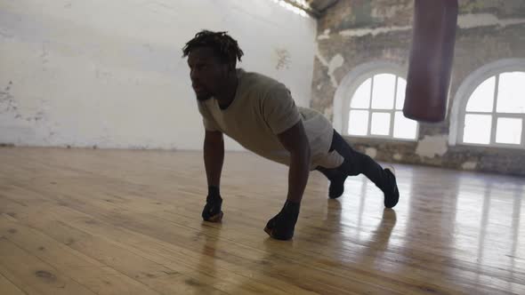Boxer Doing Pushups on the Floor While Working Out in Old Light Building alt