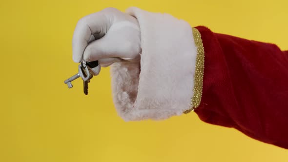 Santa Claus holding keys of new house or apartment on yellow background.