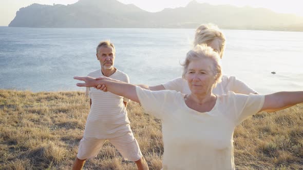 Group of Elderly People Doing Yoga at Sunset