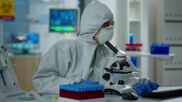 Woman Scientist in Ppe Suit Working in Lab Using Modern Microscope alt