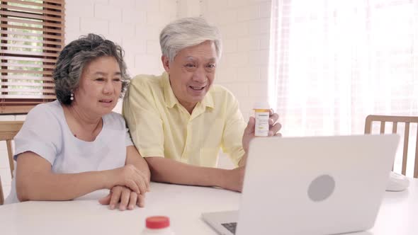 Asian elderly couple using laptop conference with doctor about medicine information in living room.