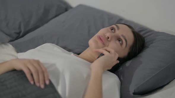 Close up of Hispanic Woman Talking on Phone while Laying in Bed alt