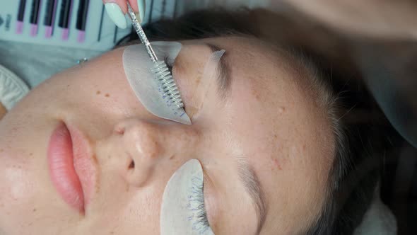 Eyelash Extension Master Combs Beautiful Readymade Eyelashes with a Brush on the Client's Eye Which alt