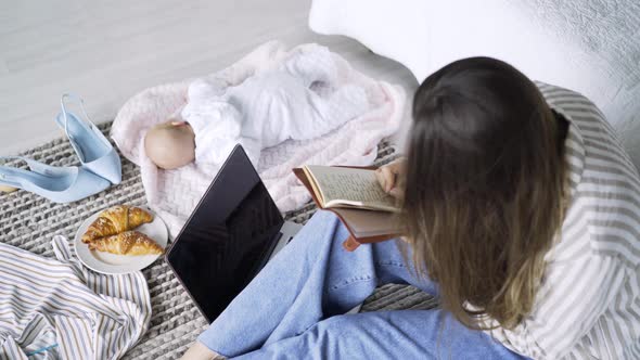 Mother Using Laptop on Carpet By Sleeping Baby