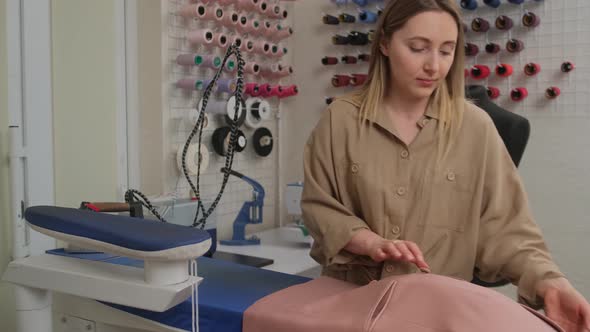 tailor straightens the jacket after ironing. Concept of handmade, couturier and tradition. alt