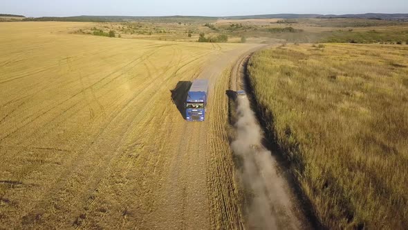 Top down aerial view of fast driving car on dirt road leaving cloud of dust behind. alt