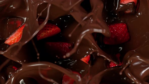 Super Slow Motion Shot of Fresh Cutted Strawberries Falling Into Melted Chocolate at 1000 Fps alt