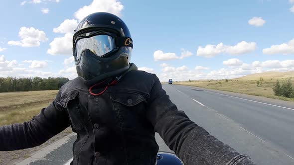 Man in Helmet Rides Motorcycle on Highway. Man with Helmet and Windproof Glasses and Clouds alt