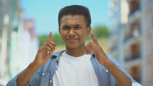 Afro-American Teen Guy Suffering Loud Street Noise, Closing Ears by Fingers alt