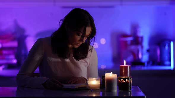 Mysterious Atmosphere at Night in Room of Young Woman Reading Book By Candlelight in Darkness alt