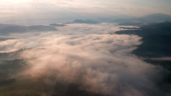 Low clouds and morning mists over mountain slopes at sunrise alt