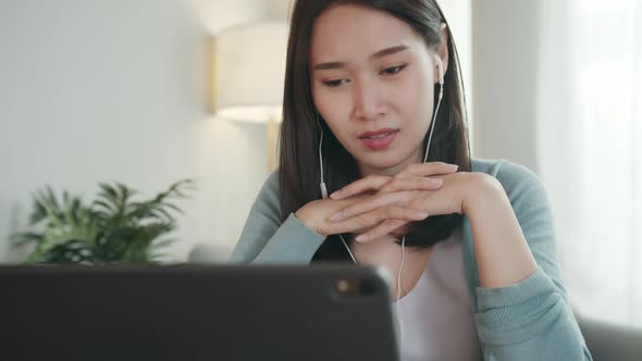 Beautiful Asian Businesswoman or freelancer wears earphones having video call conference