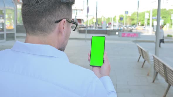 Man Using Smartphone with Green Screen Outdoor alt