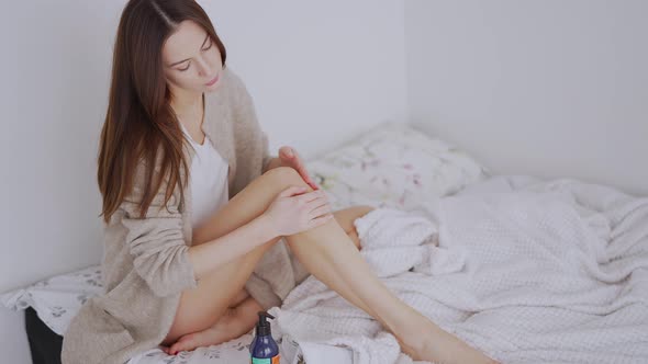 Woman Smearing Cream on Leg on Bed alt