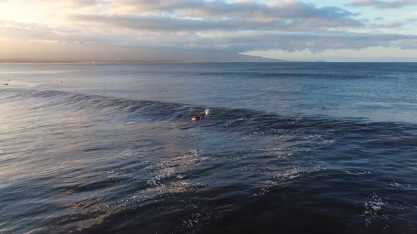 surfer attempting to ride wave and another duck dives it during sunrise in hawaii alt