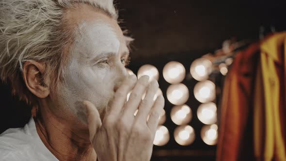 Performer Smudges White Paint on Face for Show in Circus alt