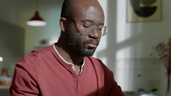 African American Man Using Laptop in Evening at Home alt