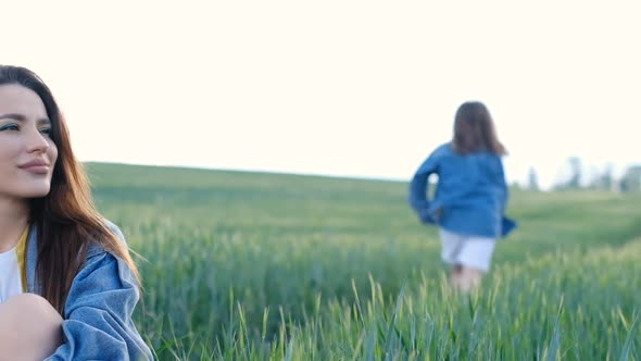 Beautiful Woman Mom and Daughter Running in the Middle of the Field on a Background of Sky alt