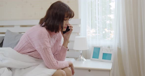 Young woman talking mobile phone and crying in bedroom
