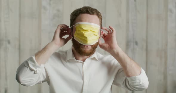 Attractive Young Man Shows How to Properly Put on a Medical Mask